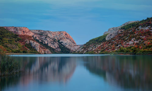 Scenic view of lake by mountains against sky