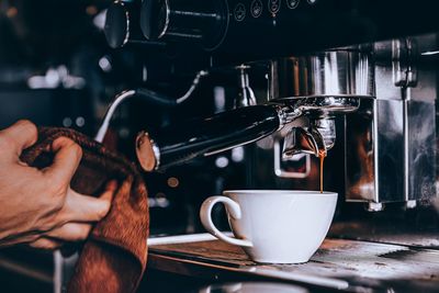 Cropped hand pouring coffee on table