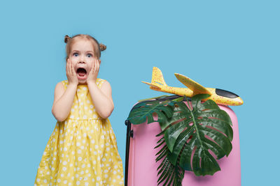 Portrait of a girl standing against blue background