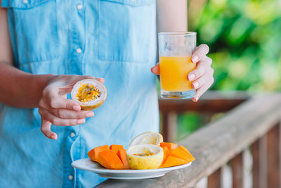 Midsection of woman holding fruits and juice