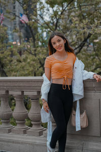 Portrait of young woman standing against wall