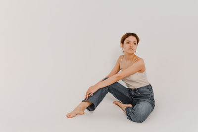 Portrait of young woman standing against white background