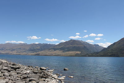 Scenic view of lake and mountains against blue sky