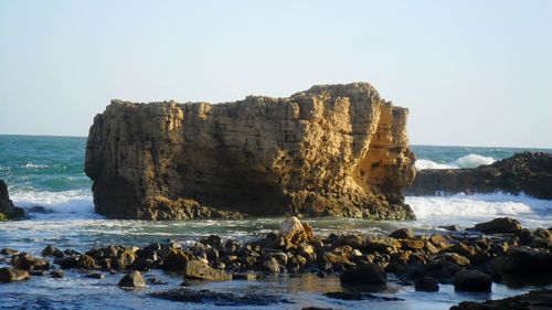 Panoramic shot of rocks on sea against clear sky