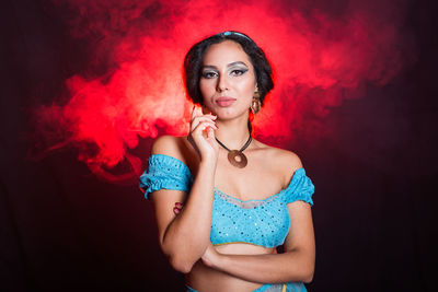 Portrait of young woman against red background