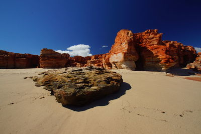 Rock formations on beach against sky