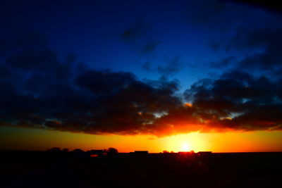 Silhouette landscape against dramatic sky during sunset