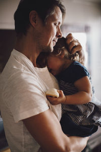 Mature father with eyes closed holding daughter in arms