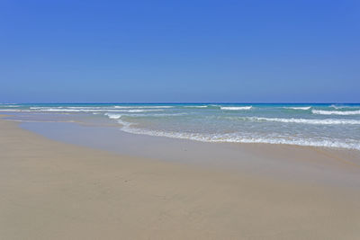 Scenic view of beach against clear blue sky