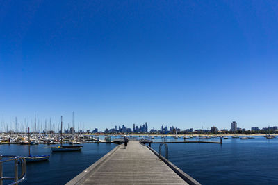 Sailboats in sea against clear blue sky