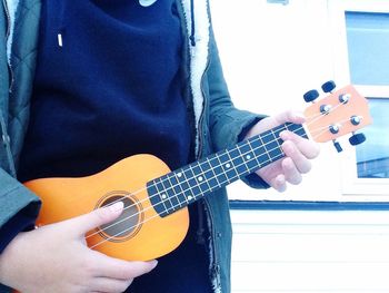 Midsection of man playing guitar