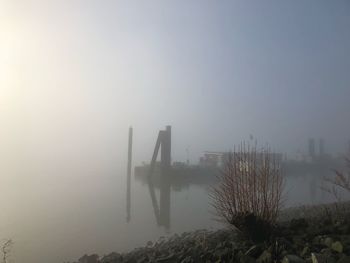 Scenic view of foggy weather against sky during winter