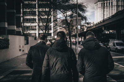 Rear view of men walking on street in city