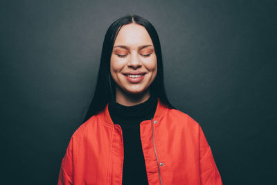 Young woman with eyes closed over gray background