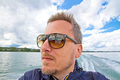 Portrait of mature man on sea against cloudy sky