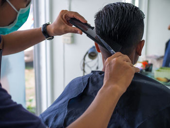 Cropped hands of hairdresser cutting man hair