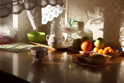 Variety of fruits with teapot and cup on table in kitchen