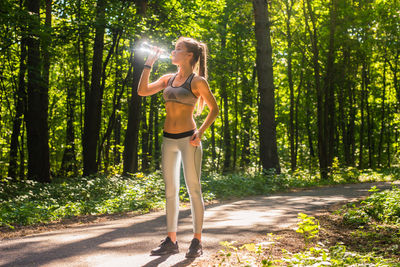 Full length of woman standing by tree in forest