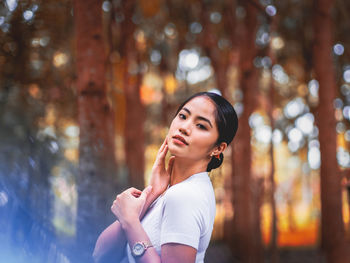 Portrait of smiling young woman standing against tree