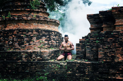 Full length of man with hands clasped at temple