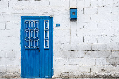 Closed blue door against white concrete wall house