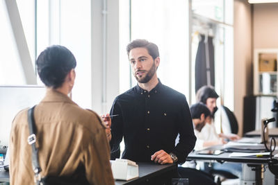 Businessman giving card to female entrepreneur at counter in office