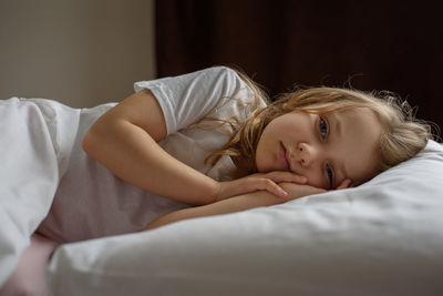 Portrait of cute girl lying on bed at home