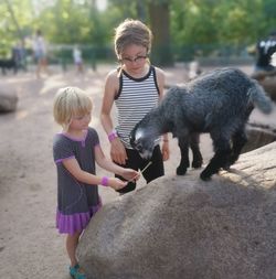 Girls playing with goats on the farm