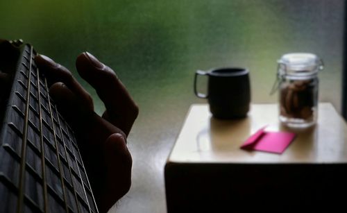 Cropped image of person playing guitar at home