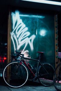 Bicycles parked on illuminated wall at night