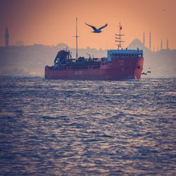 Boat sailing in sea against clear sky at sunset