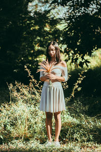 Portrait of young woman standing against tree