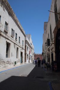 People walking on street in city against clear sky