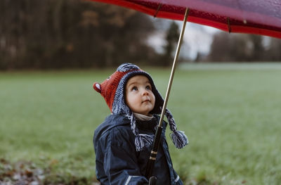 Close-up of girl holding umbrella while standing on field