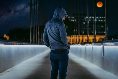 Rear view of man standing on footpath in city at dinner