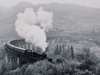 Scenic view of mountains and a steam train on a viaduct 