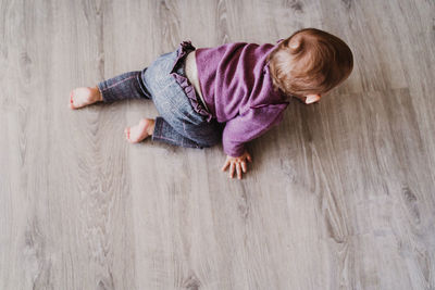 High angle view of baby lying on hardwood floor