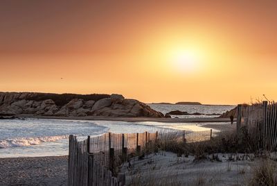 Wooden posts on beach against clear sky during sunset