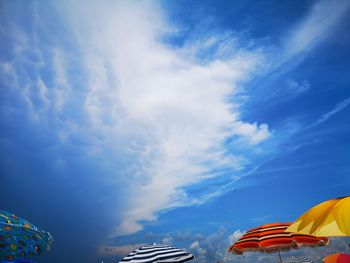 Low angle view of multi colored umbrellas against blue sky