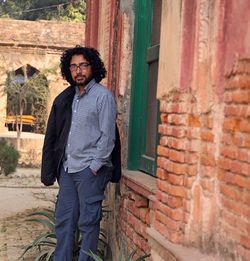 Young man standing against brick wall