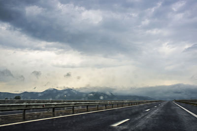 Empty road against cloudy sky