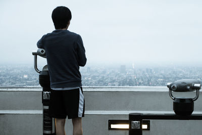 Rear view of man standing on scenic lookout over cityscape