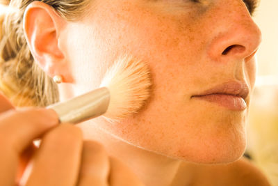 Close-up of woman applying make-up with brush