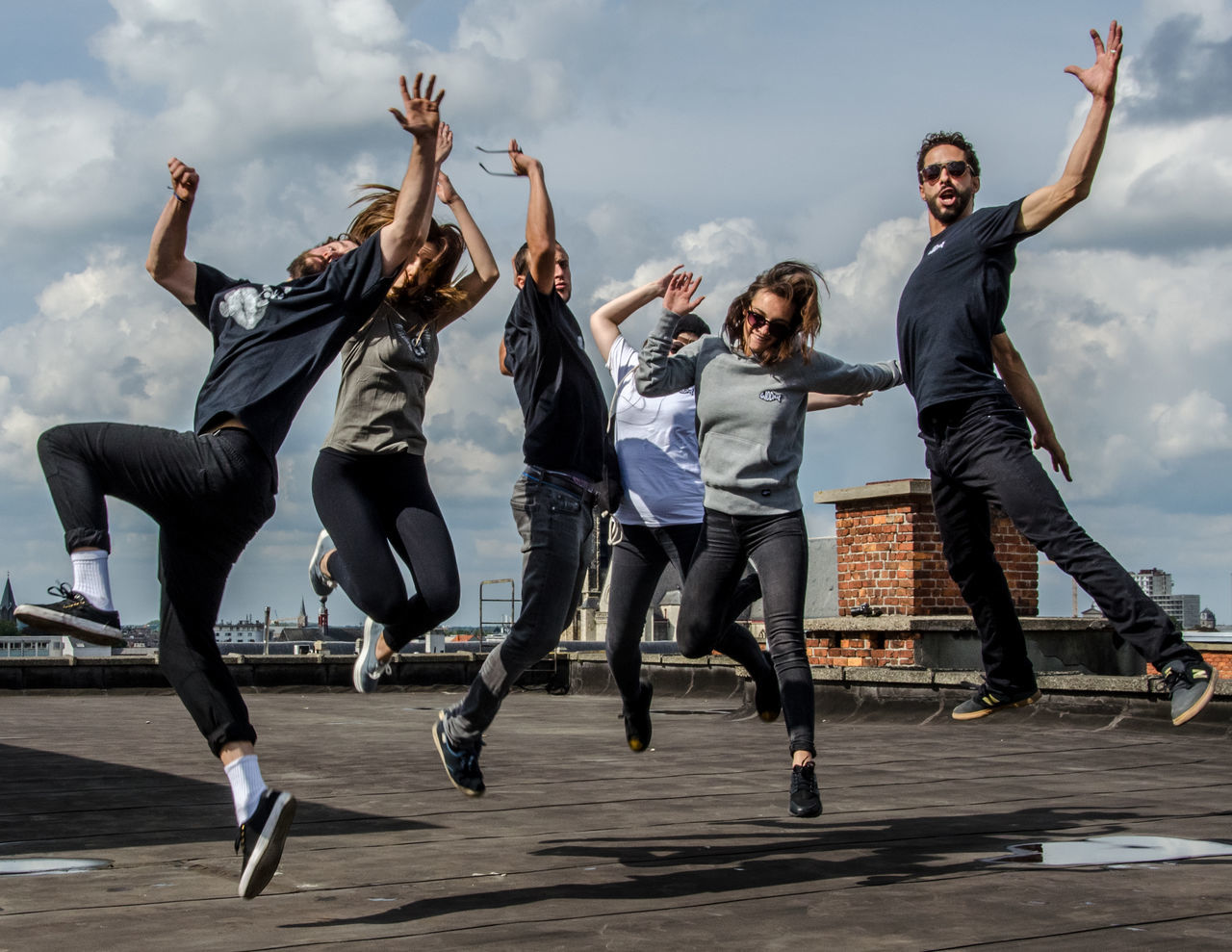 jumping, full length, motion, leisure activity, mid-air, sky, vitality, dancing, real people, outdoors, day, lifestyles, enjoyment, casual clothing, fun, cloud - sky, skill, low angle view, men, smiling, togetherness, happiness, friendship, energetic, breakdancing, young adult