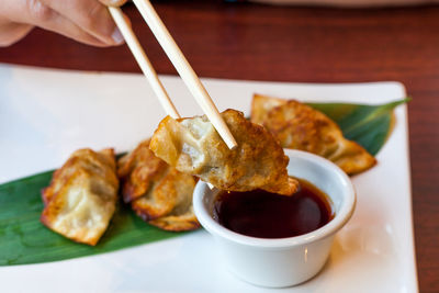 Close-up of hand holding food in plate on table