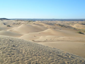 Scenic view of sand dunes against clear blue sky