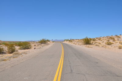 Road amidst landscape against clear blue sky