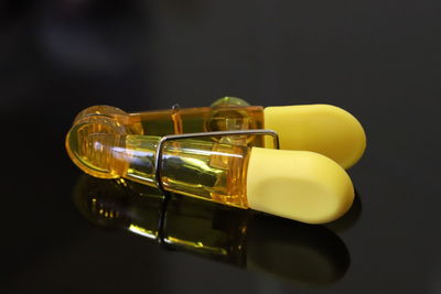 Close-up of yellow glass on table against black background