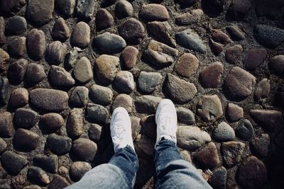 Low section of man standing on pebbles