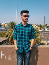 Young man in sunglasses standing against clear sky